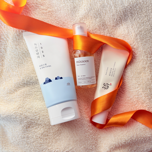 Sunny side up with the Round Lab's Dokdo Cleanser, mixsoon Bean Essence and Beauty of Joseon viral sunscreen all binded with an orange bow on a piece of a towel