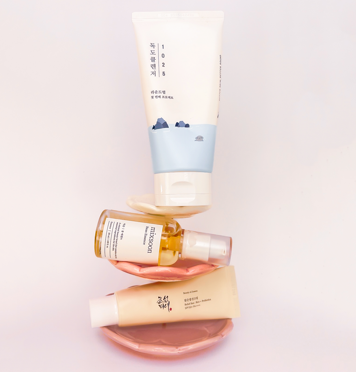 Ein Turm von 3 Skincare-Produkte - von oben nach unten - Dokdo 1025 Cleanser vom Round Lab als Schritt 1, Schritt 2 - Mixsoon Bean Essence, Schritt 3 - Beauty of Joseon Sonnenschutz.