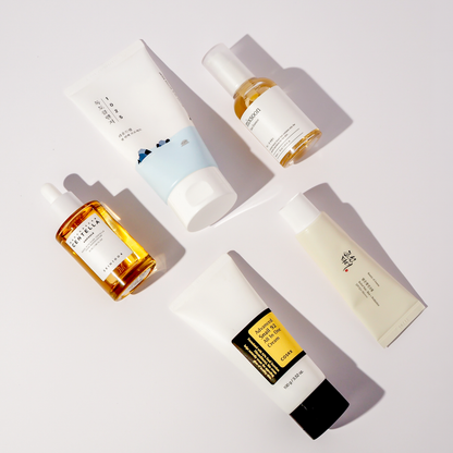 Flatlay von fünf K-Beauty Produkten: Round Lab 1025 Dokdo Creme, mixsoon Bean Essence, SKIN1004 Madagascar Centella Ampoule, COSRX Advanced Snail 92 All In One Cream und Beauty of Joseon Relief Sun Cream SPF50+ PA++++